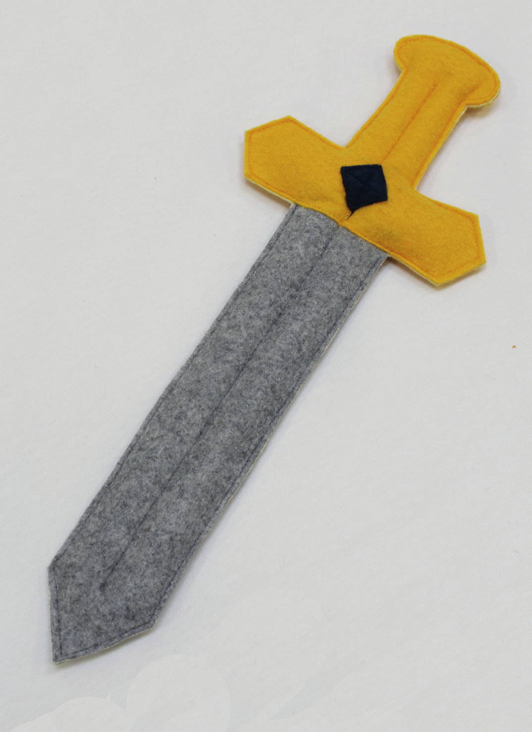 Sy det gule skaft oven på den grå klinge. Sy den blå firkant fast på skaftet. (se billede) Gentag ved den anden side af sværdet.