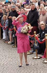 Blæsten havde rigtig godt fat i dronningens hat, men den fløj ingen steder. Langs den røde løber stod modtagelseskomiteen klar.