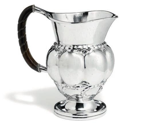 1108 1108 GEORG JENSEN b. Rådvad 1866, d. Hellerup 1935 Hammered silver pitcher with stylized ornamentation and black ebonite handle. Georg Jensen anno 1919. Designed 1907. Design no. 7.