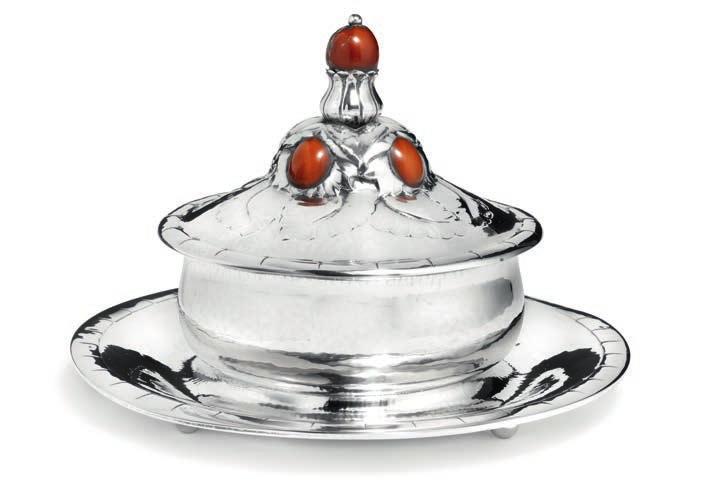 1112 1112 GEORG JENSEN b. Rådvad 1866, d. Hellerup 1935 Circular silver butter dish with leaves and flowers, on four feet. Cover with cabochon cut amber and polished amber finial.