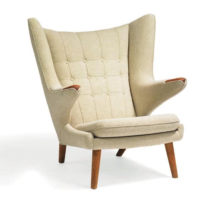 1175 HANS J. WEGNER b. Tønder 1914, d. Gentofte 2007 "Papa Bear". Wingback easy chair with teak "nails" and oak legs. Sides, seat and back upholstered with light brown wool, back fitted with buttons.