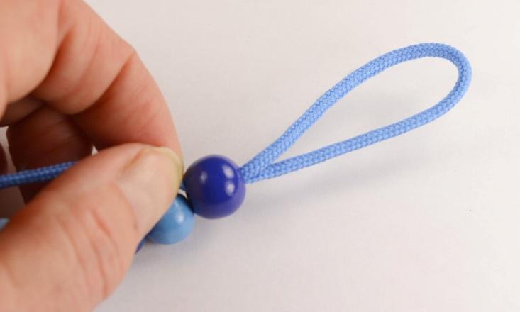 Now you pull the string to tighten all the beads towards the wood clip.