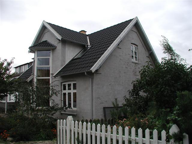 I stedet for det røde murværk, fremstår huset nu med gråfiltsede facader og taget er nylagt med støbte, sorte betontegl.
