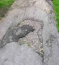 Ujævn asfalt med en del lapper og