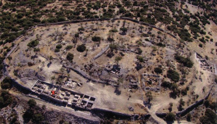 Luftfoto af Kh. Qeiyafa taget mod øst. Nederst i billedet ses vestporten og de afdækkede kasematrum. Det røde kryds viser, hvor inskriptionen blev fundet i 2008.