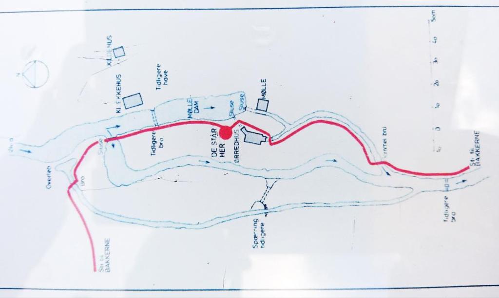 Figur 3.3: Fotografi af optegnelse over Slusegård Mølle som vist på planchen ved Møllen. Den røde streg markerer et stiforløb. Omløbsstryget v. overløbet er ikke vist på tegningen.